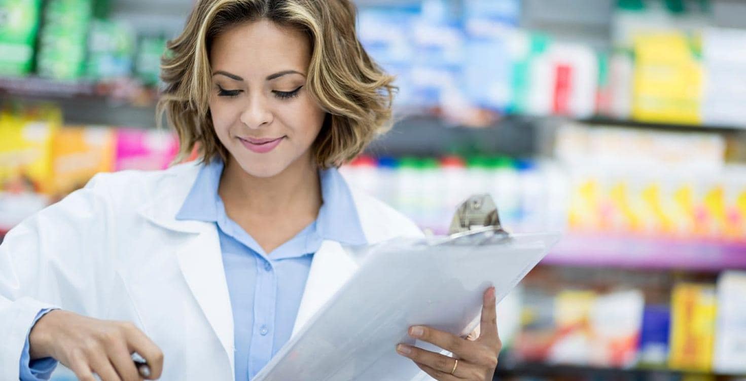 Pharmacist doing inventory at the drugstore -- woman pharmacist doing inventory at the drugstore counting medicines and holding clipboard Pharmacist doing inventory at the drugstore -- woman pharmacist doing inventory at the drugstore counting medicines and holding clipboard