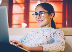 Woman with glasses on laptop smiling