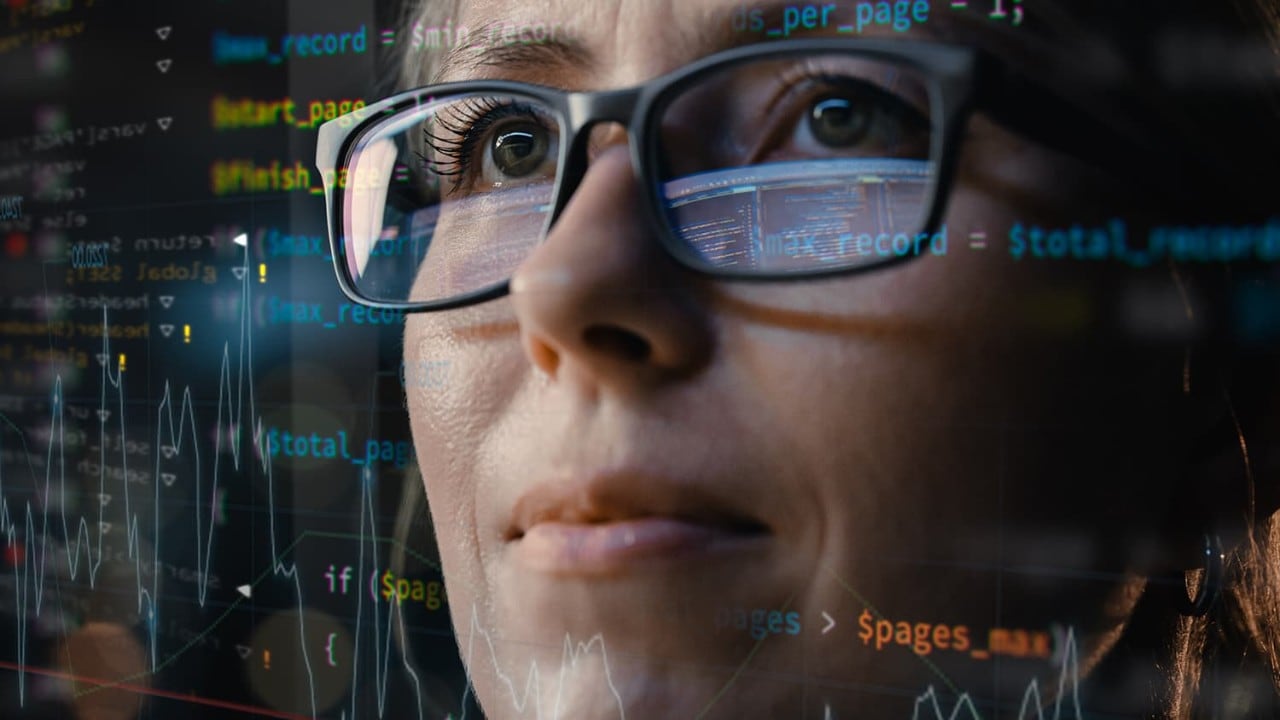 Woman with glasses immersed in code and data