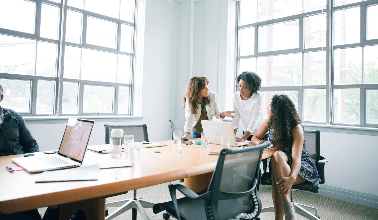 Businesswomen using laptop around a conference room table