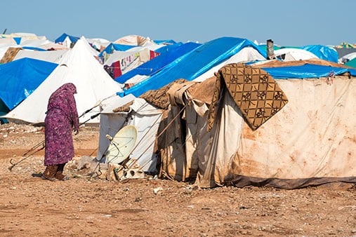 Migrant Woman Standing Beside Shelter at Camp