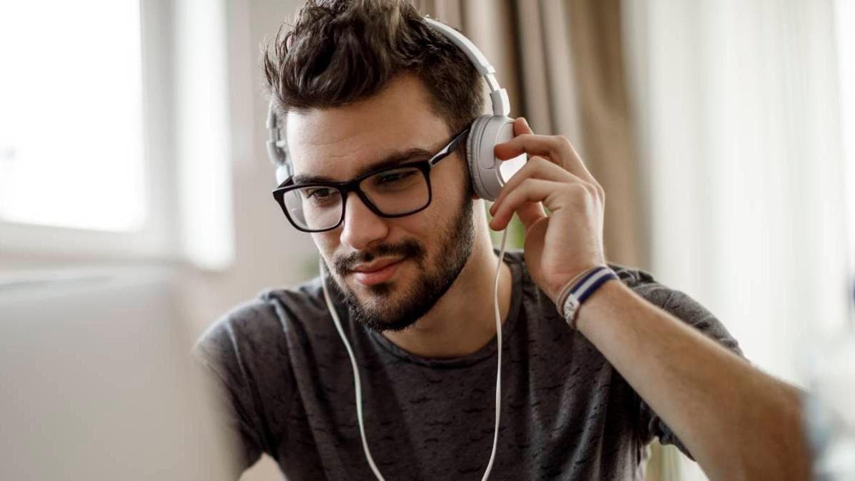 Man with glasses and headphones looking at a laptop