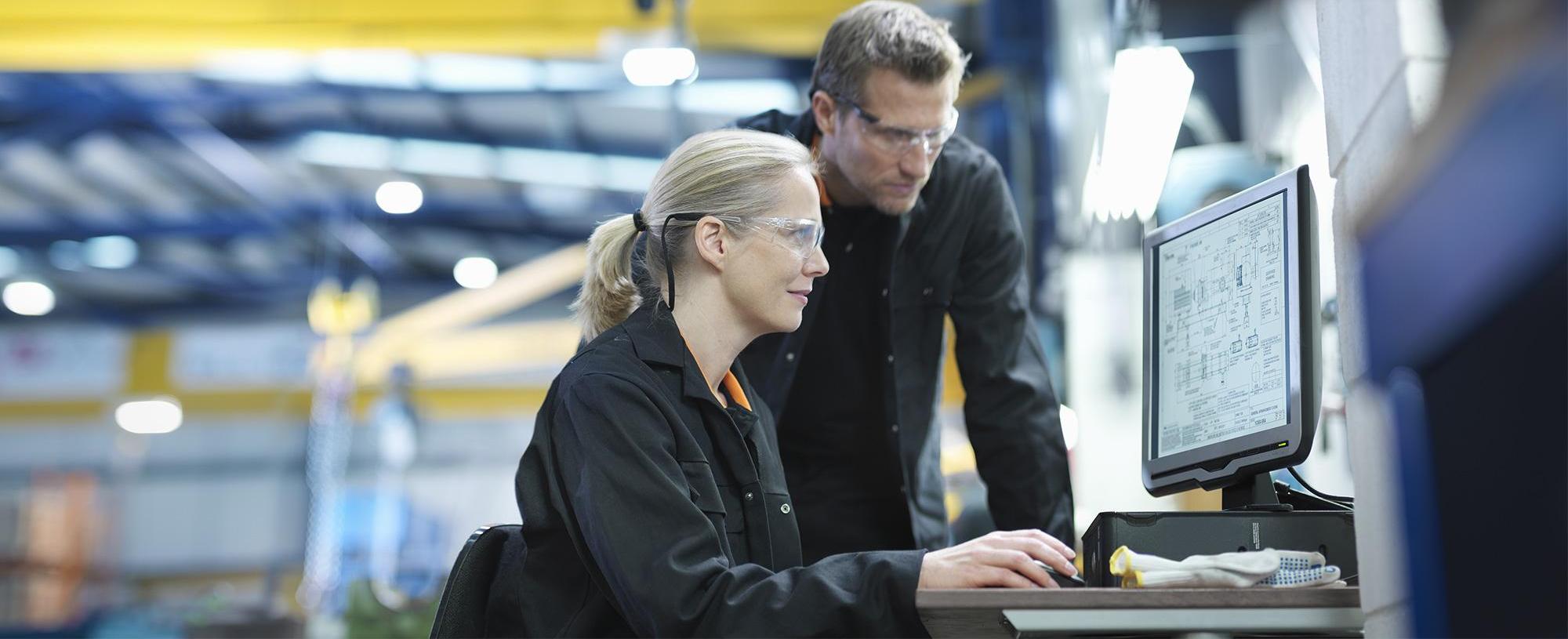 Man and woman in front of computer screen in factory