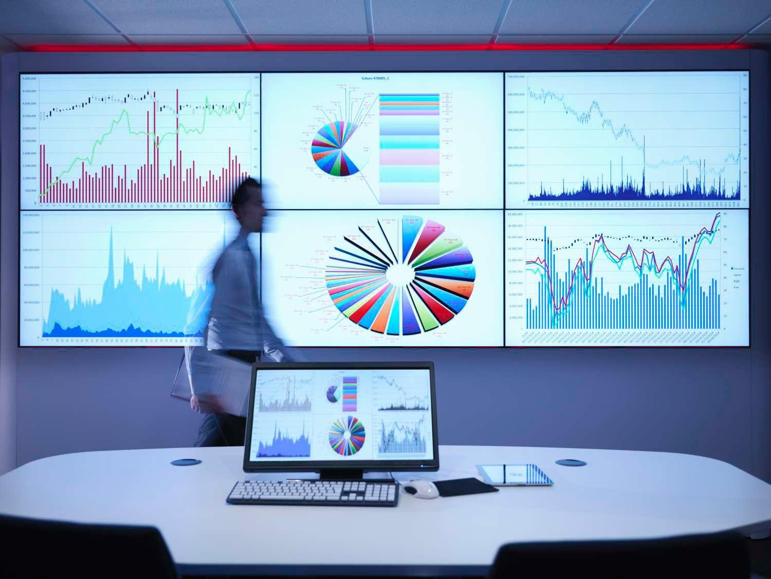 Businessman walking in front of graphs on screen 