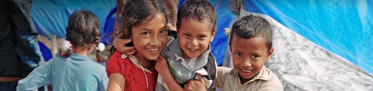 Three children smiling during relief efforts in Nepal