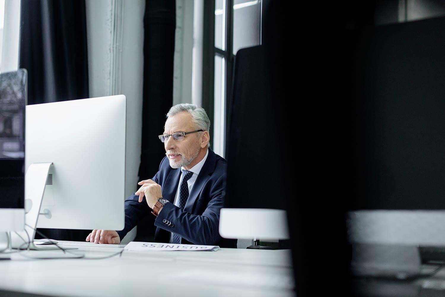 Selective focus of senior businessman working on computer in office  