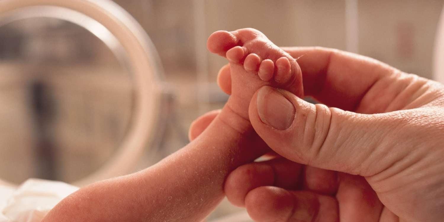 Adult hand holding infant foot