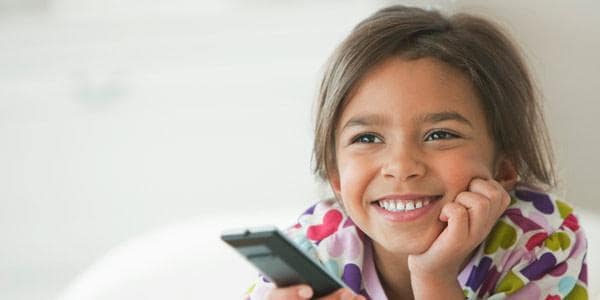 Little smiling girl holding TV remote