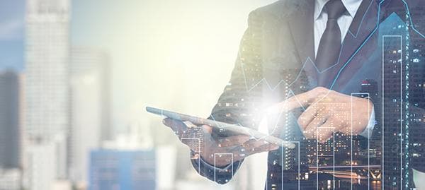 Man in suit, with a tablet on his hands and a city background