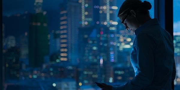 woman looking at device with dark city background woman looking at device with dark city background